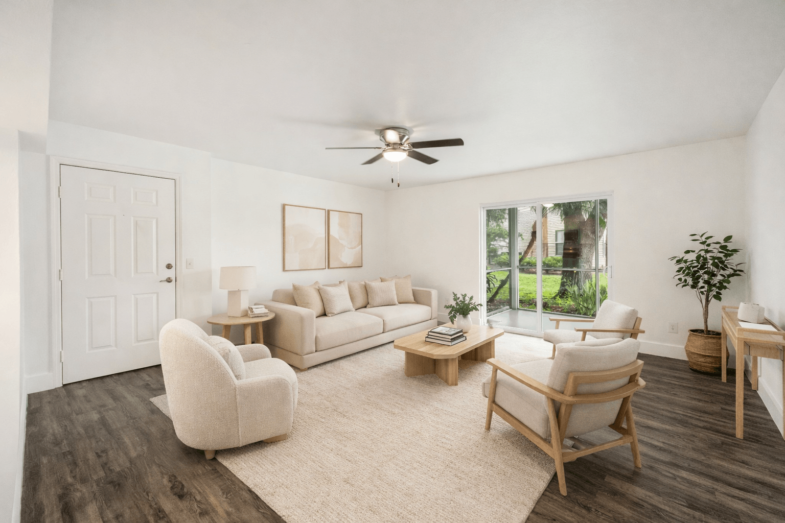 A living room with a white couch, a chair, a table, and a ceiling fan.